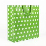 Green gift bag with white polka dots on a white background