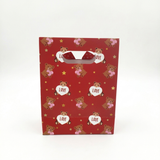 Red gift bag with teddy bear and heart designs on a white background